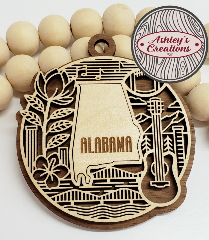 Wooden ornament with 'Alabama' design surrounded by wooden beads, branded 'Ashley's Creations'.
