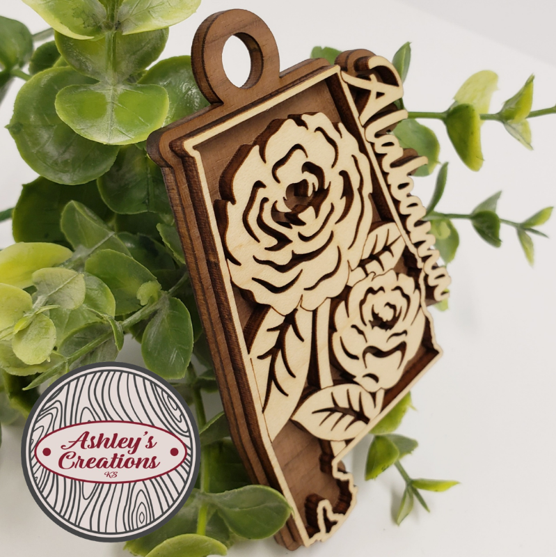 Wooden ornament with floral design on a white background with green leaves.  Made by Ashley's Creations