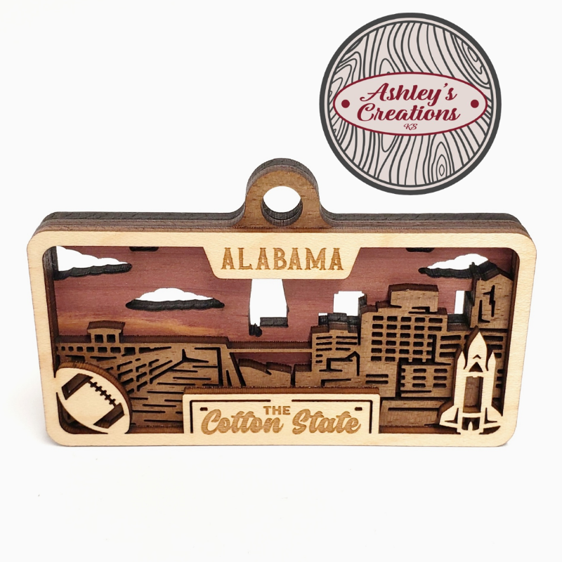 Wooden ornament with Alabama skyline and 'The Cotton State' text, branded 'Ashley's Creations'.