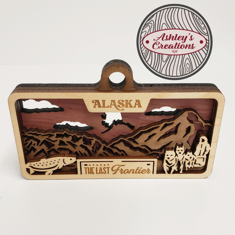 Wooden three layer license plate ornament with Alaska design and 'Ashley's Creations' logo.
