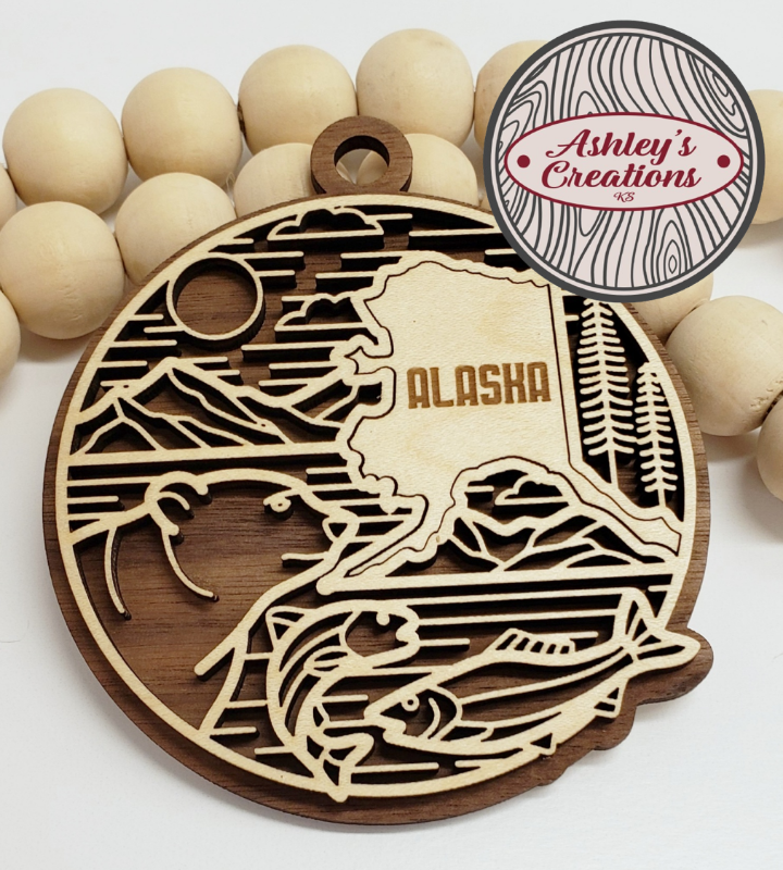 Wooden ornament with Alaska design and 'Ashley's Creations' logo.