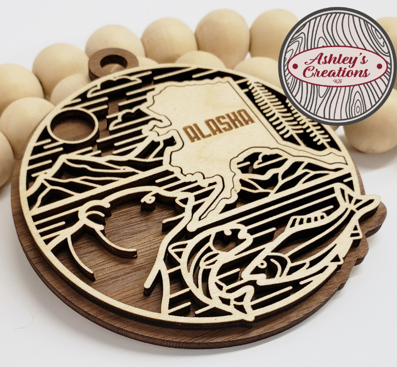 Wooden cutout of Alaska with a bear design, branded 'Ashley's Creations'.