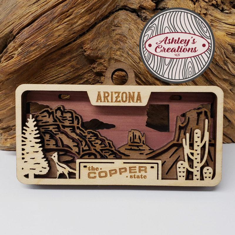 Wooden Arizona-themed license plate with desert landscape design on a wooden background
