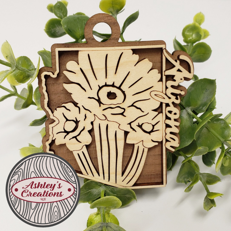 Wooden ornament with floral design and 'Arizona' text on green leaves, branded 'Ashley's Creations'.