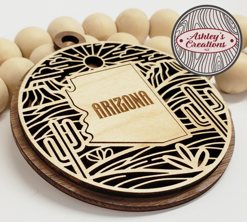 Wooden ornament with 'Arizona' engraving on a white background, branded 'Ashley's Creations'.
