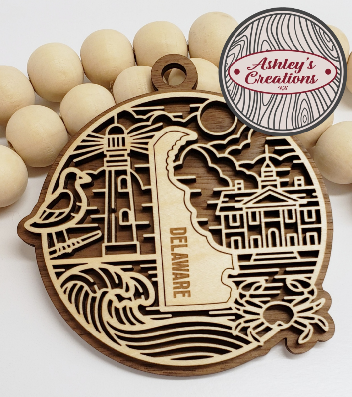 Wooden ornament with laser-cut designs and 'Delaware' text, surrounded by wooden beads, with 'Ashley's Creations' logo.