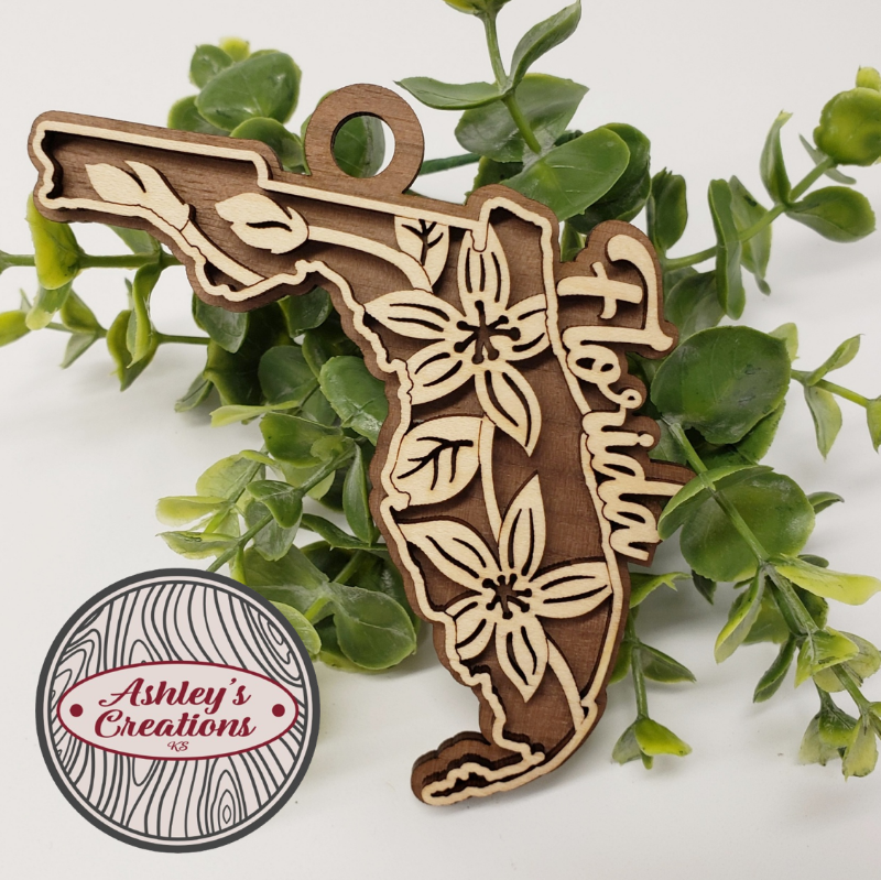 Wooden ornament of Florida with floral designs on a white background with green leaves.