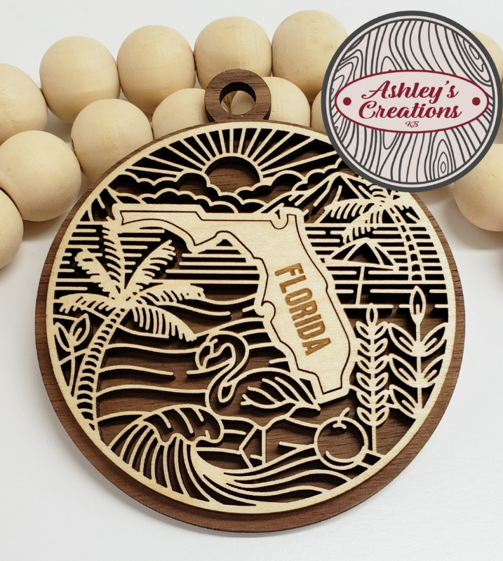 Wooden ornament with Florida design and palm tree, surrounded by wooden beads, branded 'Ashley's Creations'.