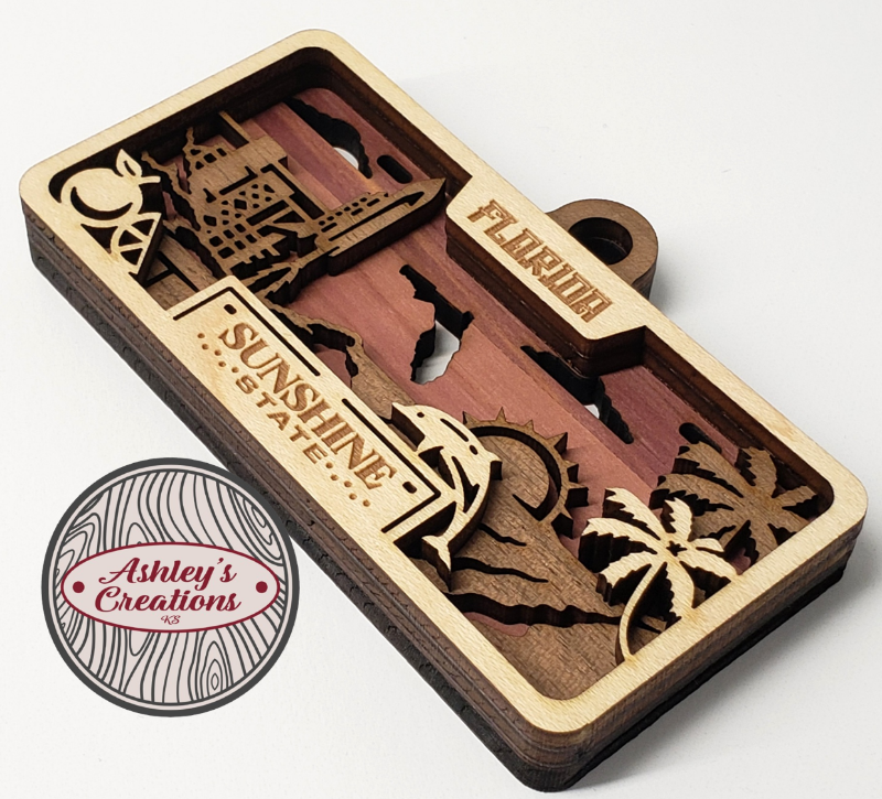 Wooden three layer license plate ornament with engraved designs and 'Sunshine State' branding on a white background.