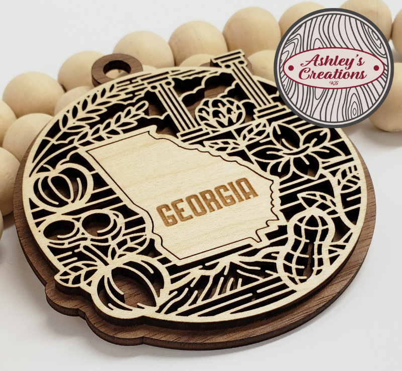 Wooden ornament with 'Georgia' engraved, surrounded by wooden beads, branded 'Ashley's Creations'.