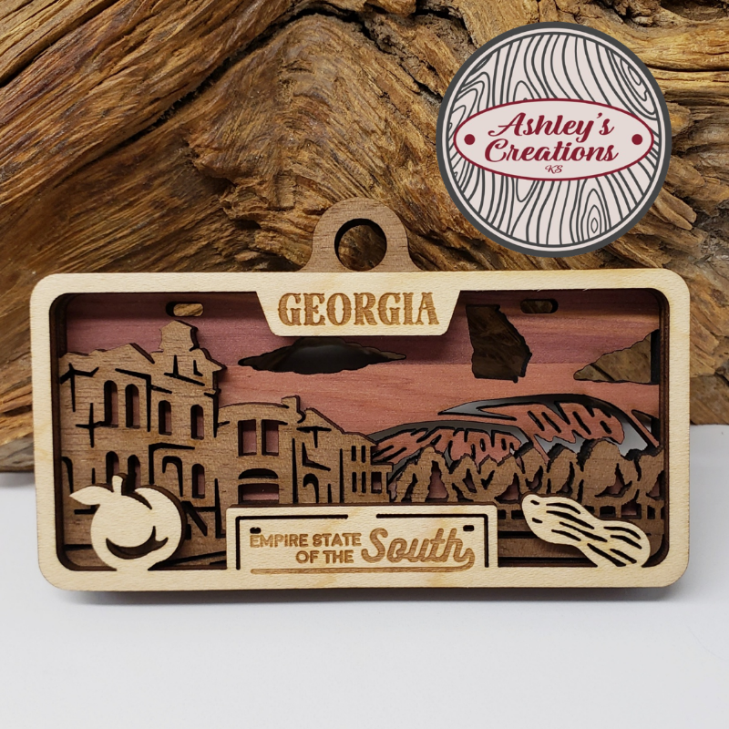 Wooden three layer license plate ornament with Georgia-themed design on a wooden background