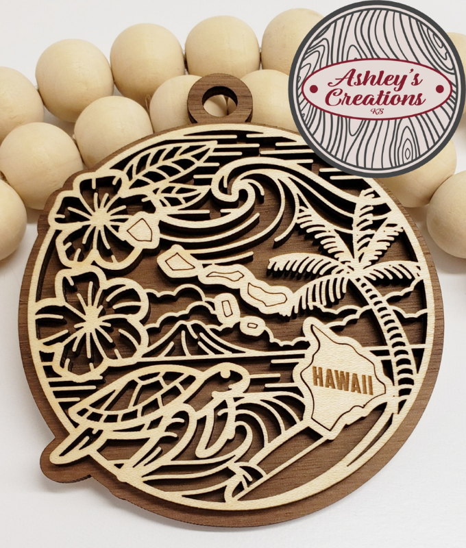 Wooden ornament with Hawaiian design surrounded by wooden beads, branded 'Ashley's Creations'.