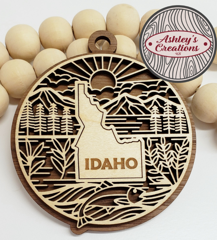 Wooden ornament with Idaho design surrounded by wooden beads, branded 'Ashley's Creations'.