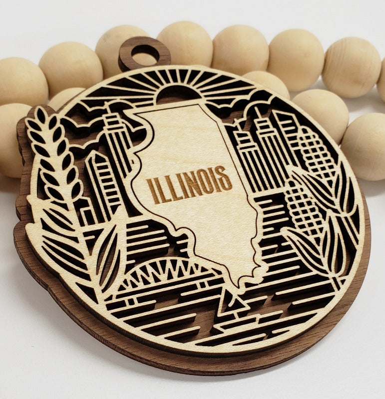 Wooden ornament with laser-cut design of Illinois and 'Illinois' text, surrounded by wooden beads.
