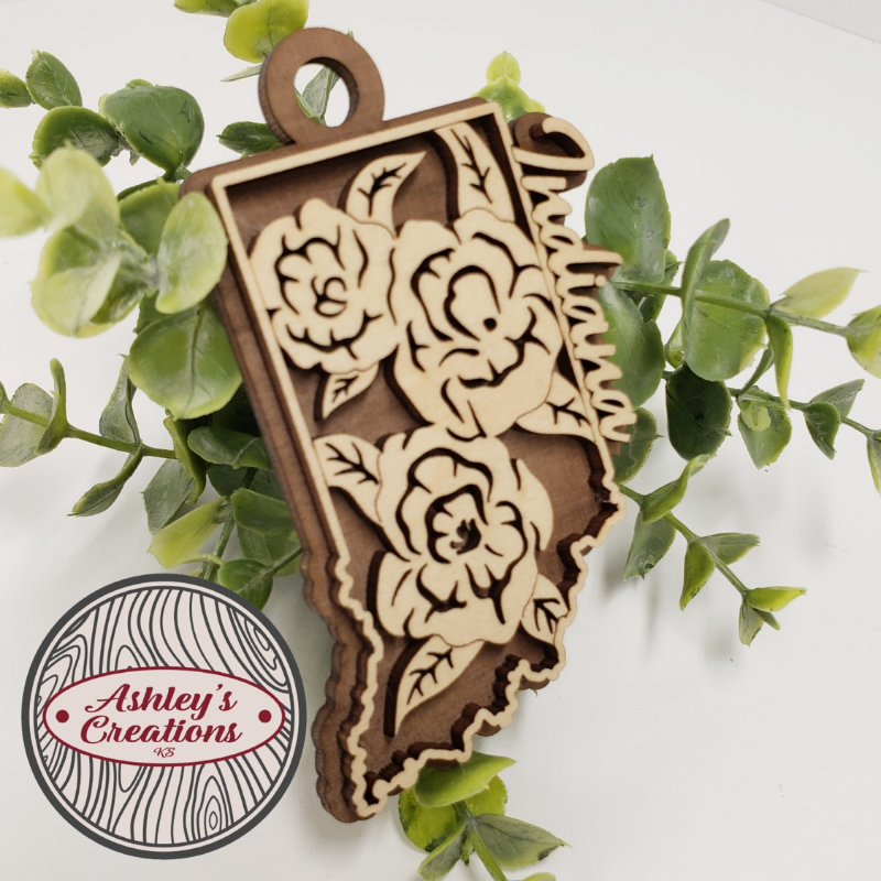 Wooden ornament with floral patterns on a white background with green leaves.