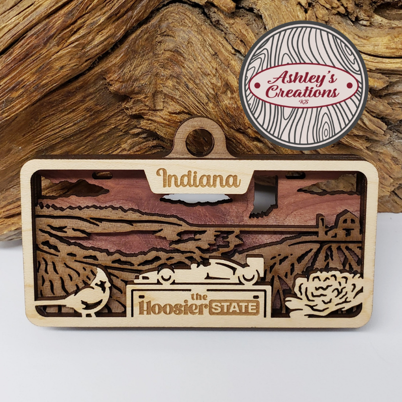 Wooden ornament item with 'Indiana' and 'the Hoosier State' text, branded 'Ashley's Creations'.