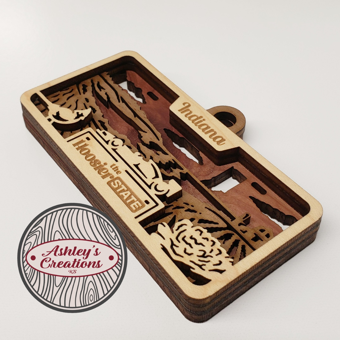 Wooden ornament with laser-cut design of Indiana, featuring the text 'The Hoosier State' on a white background.