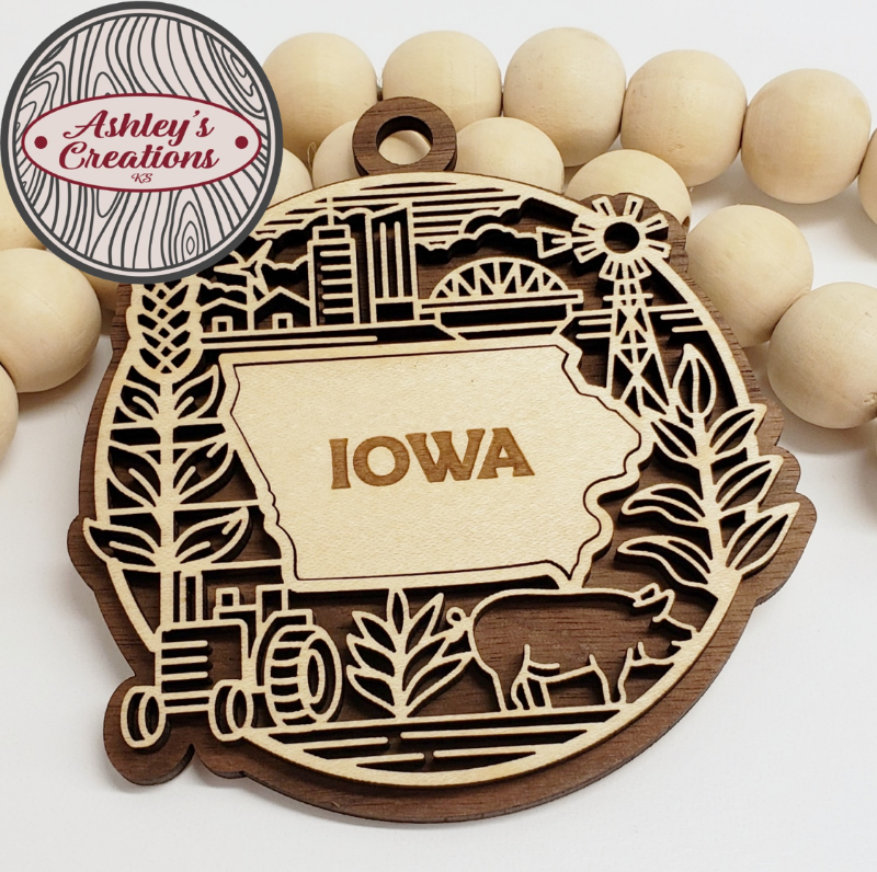 Wooden ornament with 'Iowa' design surrounded by wooden beads, featuring 'Ashley's Creations' logo.