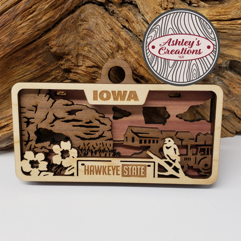 Wooden ornament with Iowa design and 'Ashley's Creations' logo in the corner.