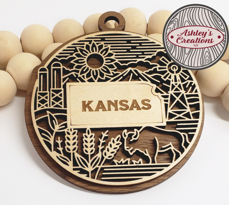Wooden ornament with 'Kansas' engraving and decorative patterns on a white background.