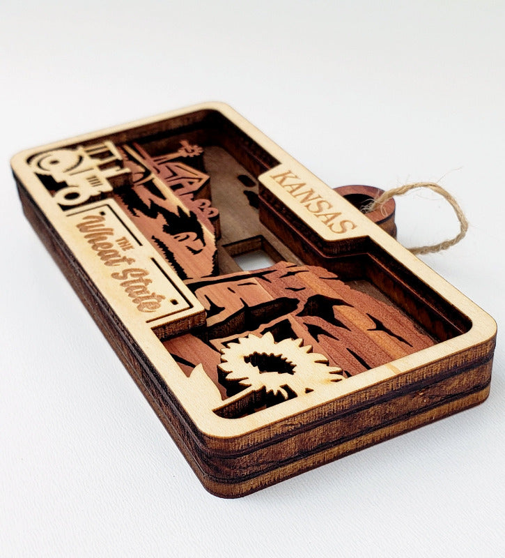 Wooden ornament with cut-out shapes and 'Kansas' text on a white background