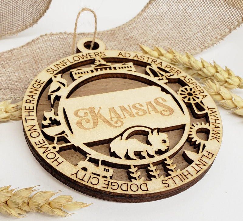 Wooden ornament with Kansas in the middle and icons from around Kansas around the edges.