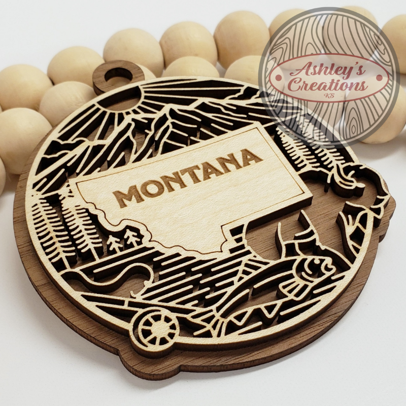 Wooden ornament with 'Montana' engraving surrounded by wooden beads, branded 'Ashley's Creations'.