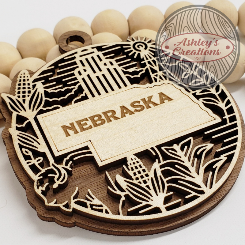 Wooden ornament with the state of Nebraska in the middle.