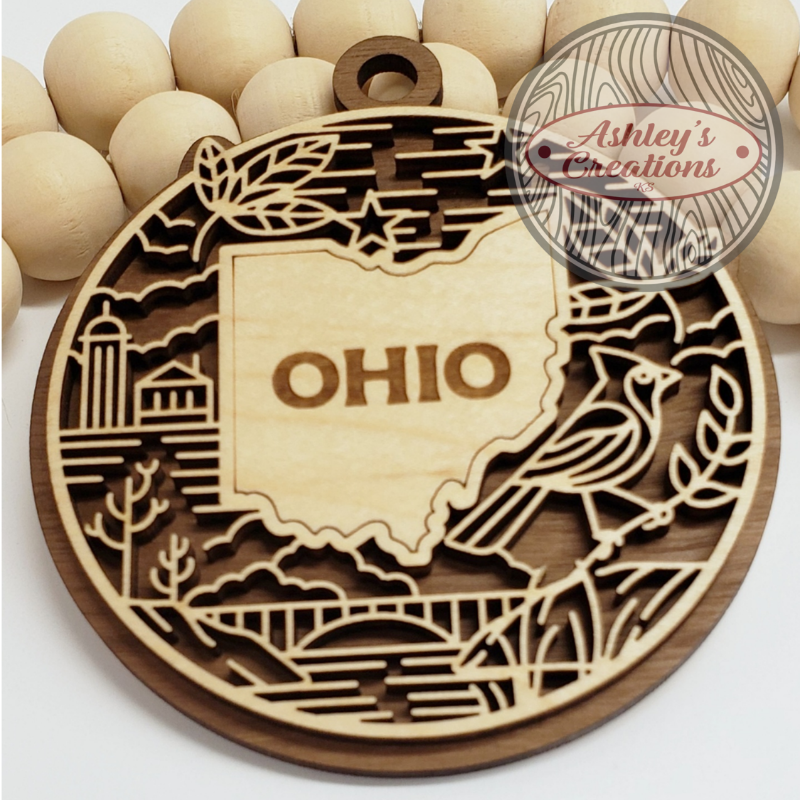 Wooden ornament with 'OHIO' and decorative elements, branded 'Ashley's Creations'.