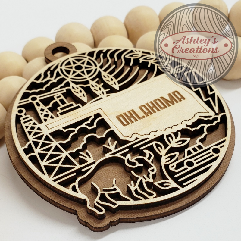 Wooden ornament with the state of Oklahoma in the middle a bison, and oil towers.