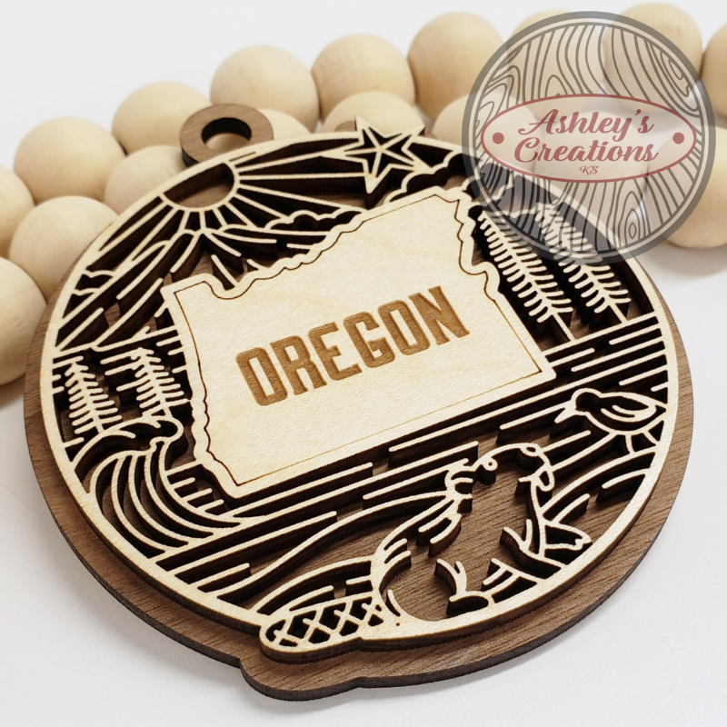 Wooden ornament with 'OREGON' engraving and laser-cut design on a white background.