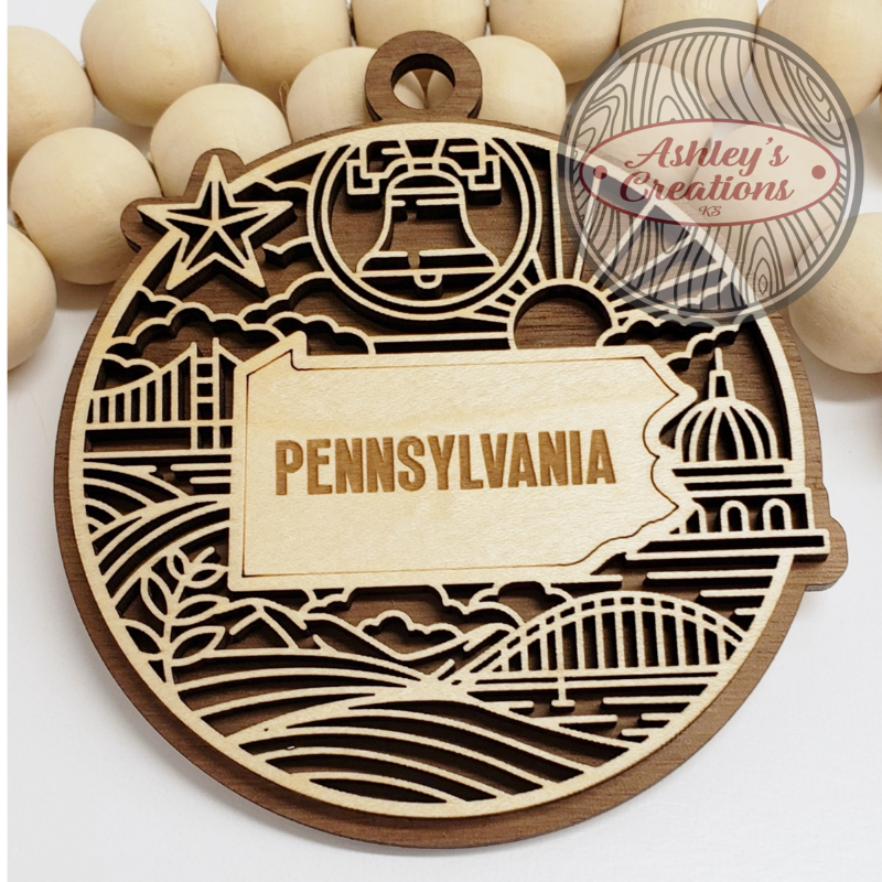 Wooden ornament with 'Pennsylvania' on a white background, featuring laser-cut designs.