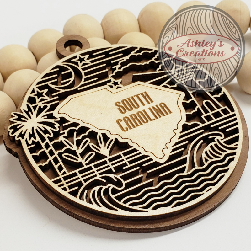 Wooden laser-cut decorative item with 'South Carolina' text, surrounded by wooden beads.