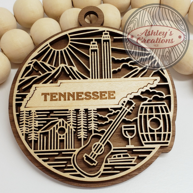 Wooden ornament with Tennessee design and guitar, barrel, and mountain elements.
