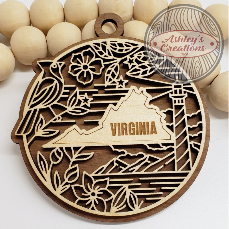 Wooden ornament with laser-cut design of Virginia, a bird, flowers, and a lighthouse on a white background.