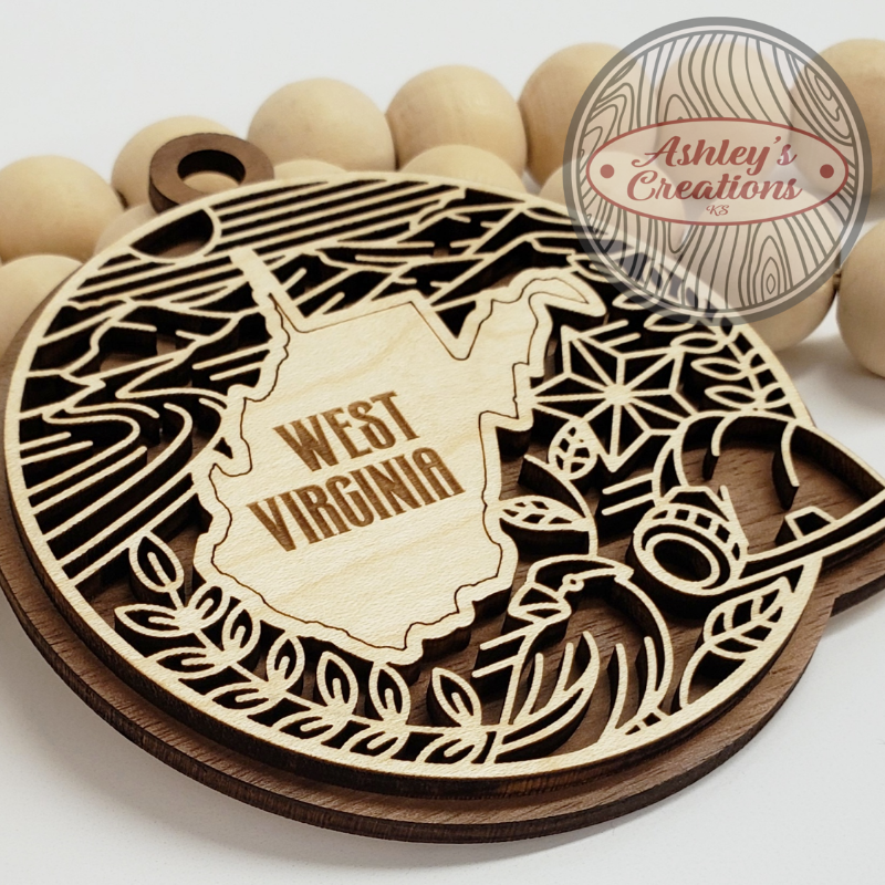Wooden cutout of West Virginia with decorative elements on a white background, branded 'Ashley's Creations'.
