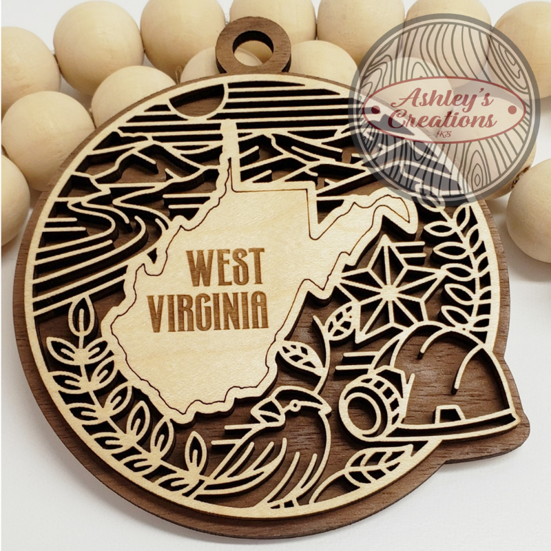Wooden ornament with West Virginia design and 'Ashley's Creations' branding.